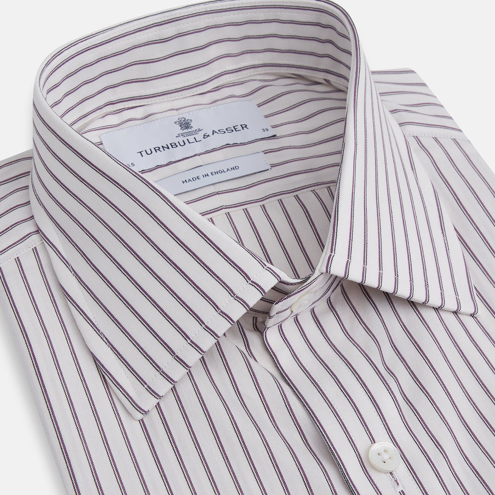 The Turnbull & Asser Purple Track Stripe Mayfair Shirt is a long-sleeve, button-up organic cotton shirt with a T&A collar, showcasing thin vertical black stripes on white and laid flat on a white surface.