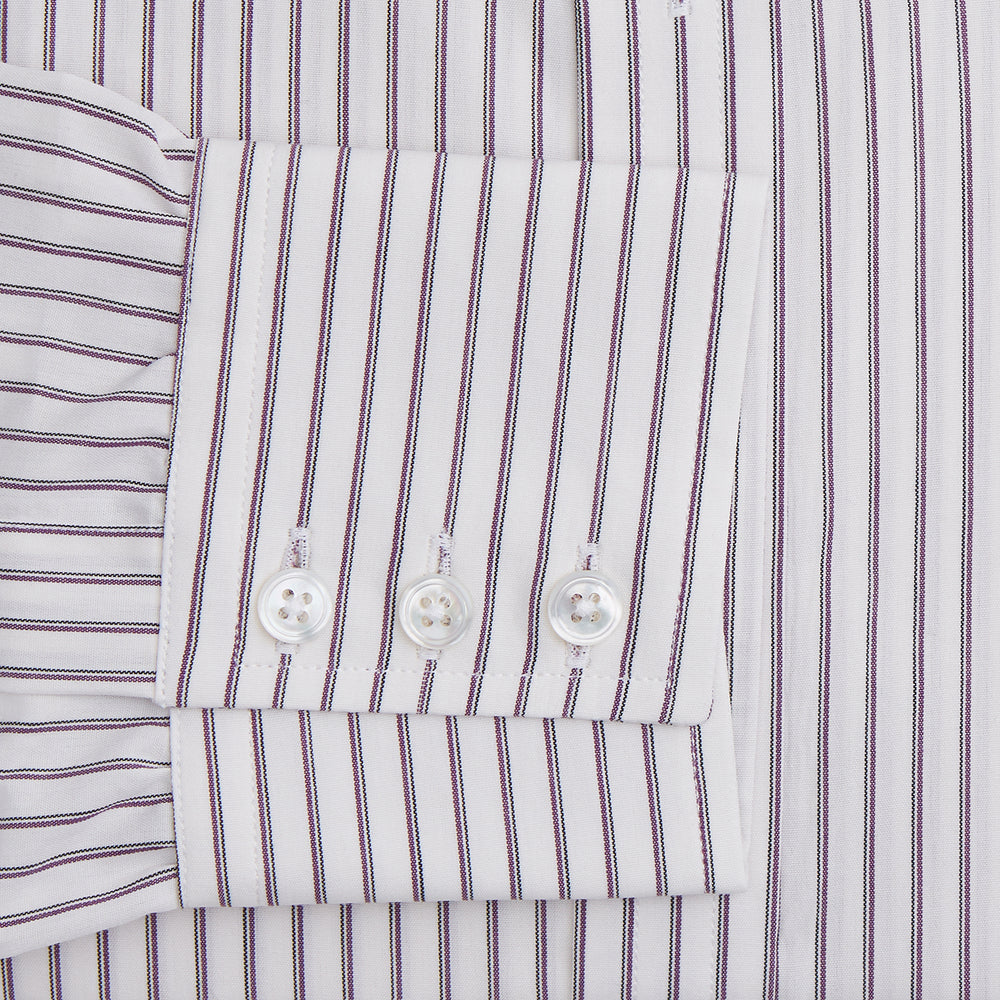 The Turnbull & Asser Purple Track Stripe Mayfair Shirt is a long-sleeve, button-up organic cotton shirt with a T&A collar, showcasing thin vertical black stripes on white and laid flat on a white surface.