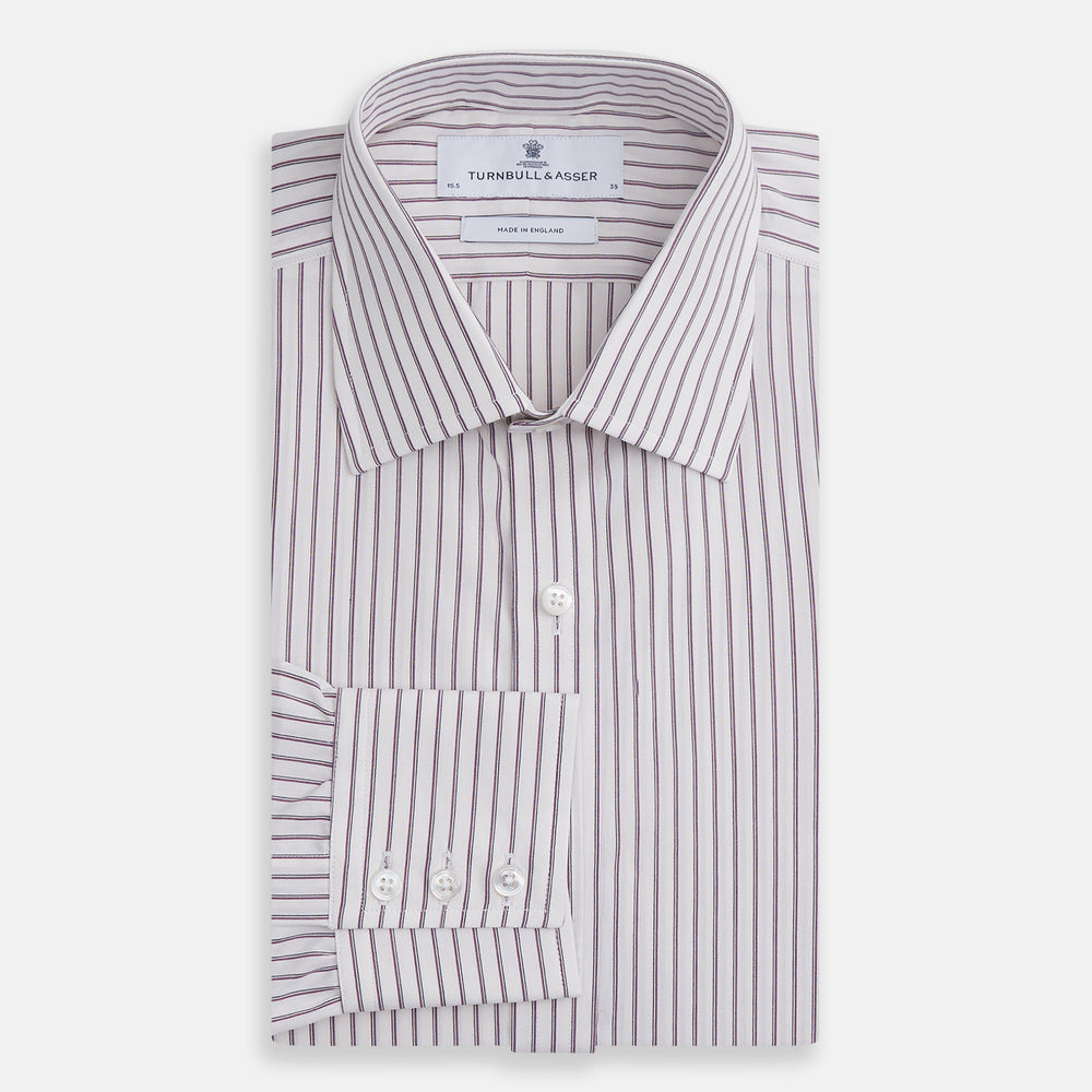 The Turnbull & Asser Purple Track Stripe Mayfair Shirt is a long-sleeve, button-up organic cotton shirt with a T&A collar, showcasing thin vertical black stripes on white and laid flat on a white surface.