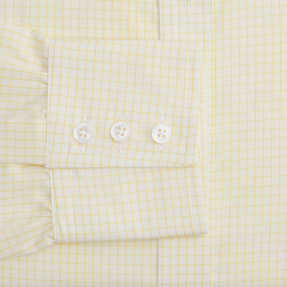The Turnbull & Asser Yellow Graph Check Mayfair Shirt features long sleeves, a button-up front, and classic T&A collar in organic cotton with a light yellow check pattern—a summer staple shown on a plain white background.
