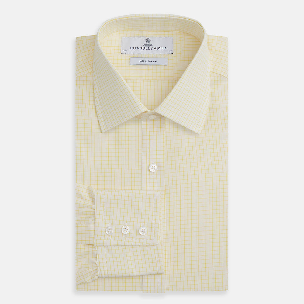 The Turnbull & Asser Yellow Graph Check Mayfair Shirt features long sleeves, a button-up front, and classic T&A collar in organic cotton with a light yellow check pattern—a summer staple shown on a plain white background.