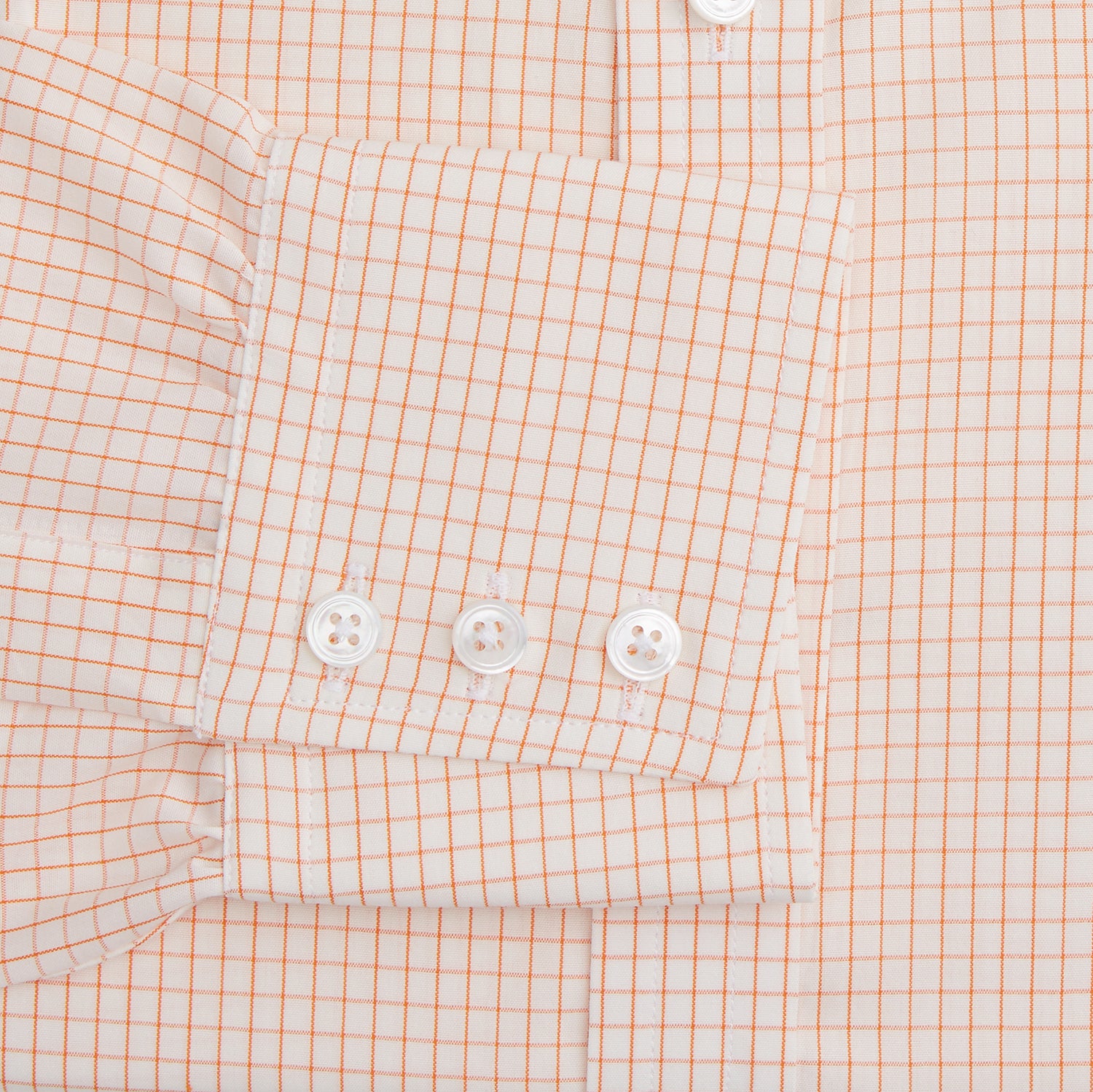 View 3 of product The Turnbull & Asser Orange Graph Check Mayfair Shirt features a classic T&A collar, long sleeves, buttoned cuffs, and a peach and white check pattern, shown against a white background.