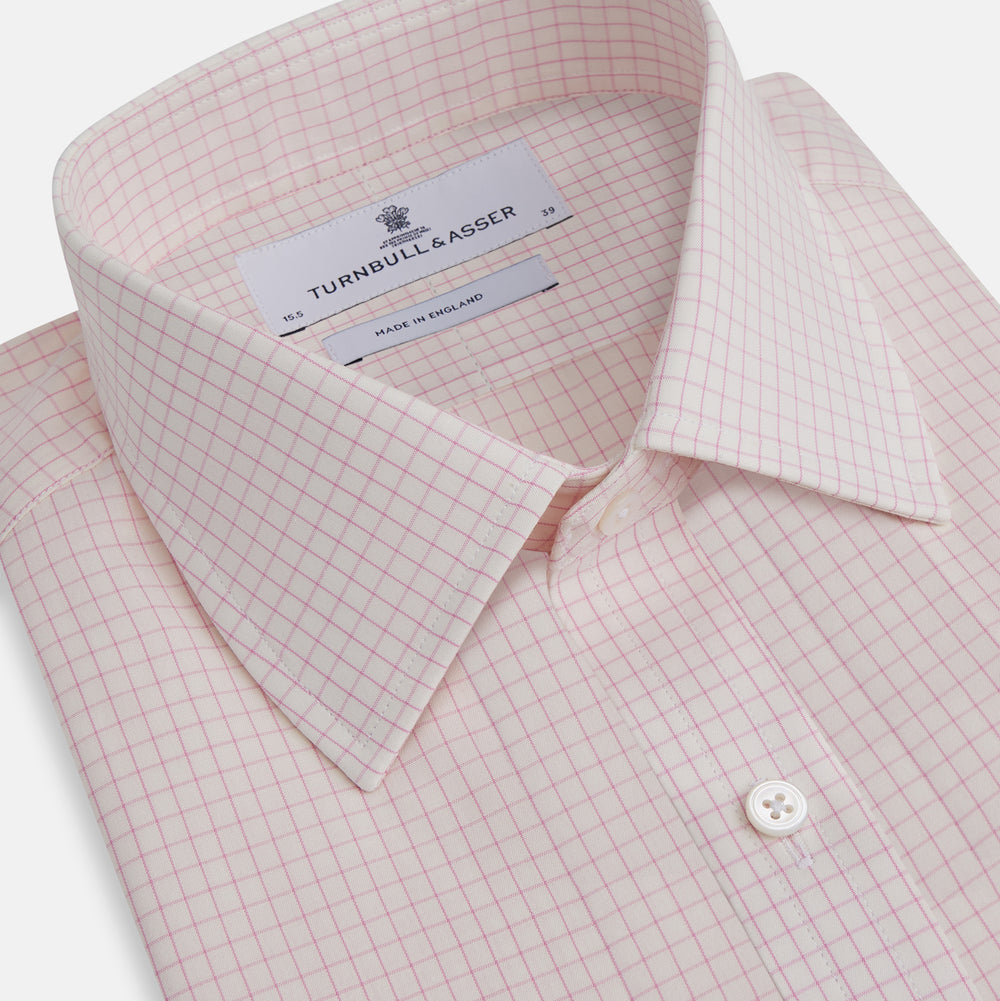 The Pink Graph Check Mayfair Shirt by Turnbull & Asser is an organic cotton, long-sleeve button-down with a classic collar and buttoned cuffs, featuring a subtle light pink and white graph check pattern, shown laid flat on a white background.