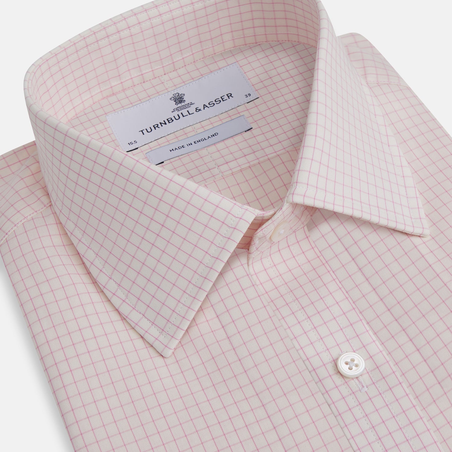 View 2 of product The Pink Graph Check Mayfair Shirt by Turnbull & Asser is an organic cotton, long-sleeve button-down with a classic collar and buttoned cuffs, featuring a subtle light pink and white graph check pattern, shown laid flat on a white background.