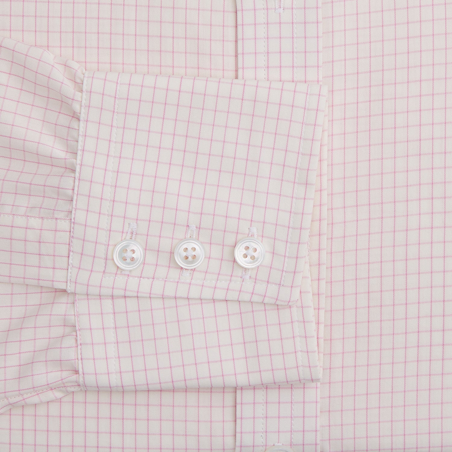 View 3 of product The Pink Graph Check Mayfair Shirt by Turnbull & Asser is an organic cotton, long-sleeve button-down with a classic collar and buttoned cuffs, featuring a subtle light pink and white graph check pattern, shown laid flat on a white background.
