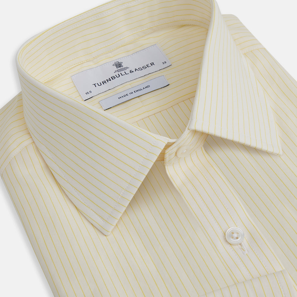 The Turnbull & Asser Yellow Pinstripe Mayfair Shirt, made from organic cotton with long sleeves, a T&A collar, and front buttons, features subtle vertical stripes and is shown on a plain white background.