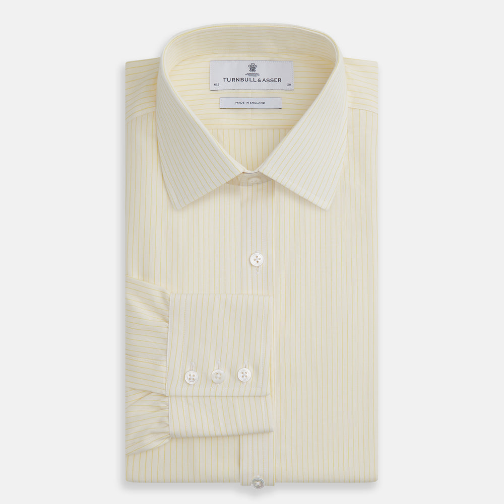 The Turnbull & Asser Yellow Pinstripe Mayfair Shirt, made from organic cotton with long sleeves, a T&A collar, and front buttons, features subtle vertical stripes and is shown on a plain white background.