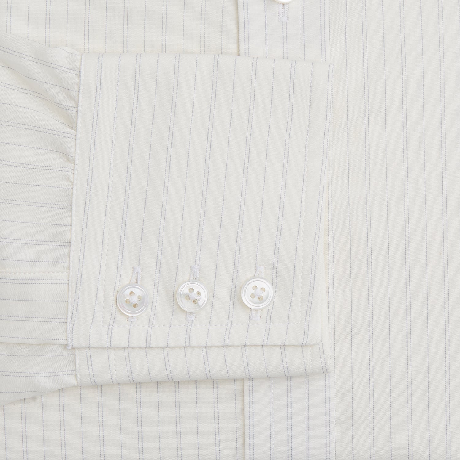 View 3 of product The Turnbull & Asser Pale Blue Fine Track Stripe Mayfair Shirt is a long-sleeve, cream-colored organic cotton shirt with subtle pale blue stripes, a T&A collar, and buttoned cuffs, shown on a plain white background.