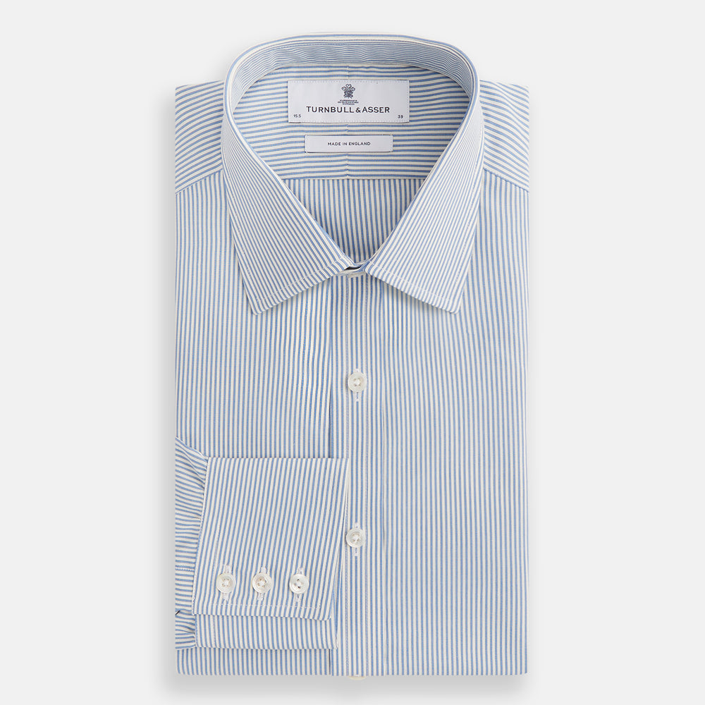 The Turnbull & Asser Blue and White Pencil Stripe Mayfair Shirt features breathable cotton, a standard collar, buttoned cuffs, and white buttons, shown laid flat on a white background.