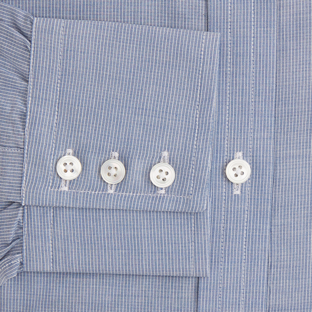The Turnbull & Asser Blue Pencil Stripe Mayfair Shirt is crafted from organic cotton with a classic collar, white buttons, and buttoned cuffs. Shown laid flat on a white background.