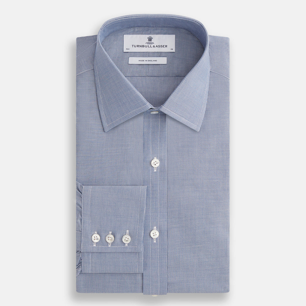 The Turnbull & Asser Blue Pencil Stripe Mayfair Shirt is crafted from organic cotton with a classic collar, white buttons, and buttoned cuffs. Shown laid flat on a white background.