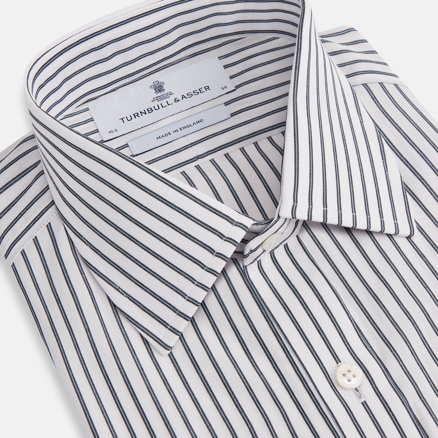 View 2 of product The Turnbull & Asser Midnight Blue Halo Stripe Mayfair Shirt features breathable cotton with black and white vertical stripes, a pointed T&A collar, and buttoned cuffs, displayed flat on a white background.