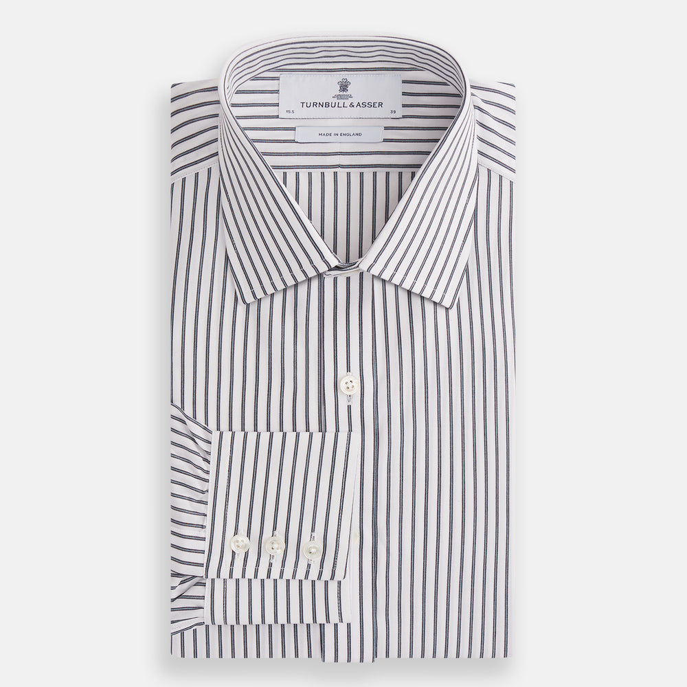The Turnbull & Asser Midnight Blue Halo Stripe Mayfair Shirt features breathable cotton with black and white vertical stripes, a pointed T&A collar, and buttoned cuffs, displayed flat on a white background.