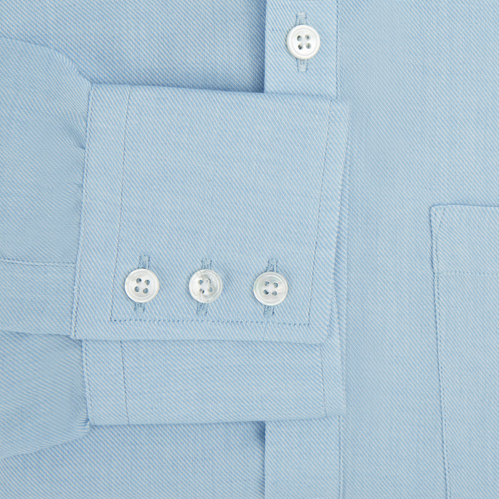 The Blue Cotton Cashmere Chelsea Shirt by Turnbull & Asser, a light blue long-sleeve button-up with a chest pocket, crafted from soft cotton and cashmere, is shown laid flat on a white background.