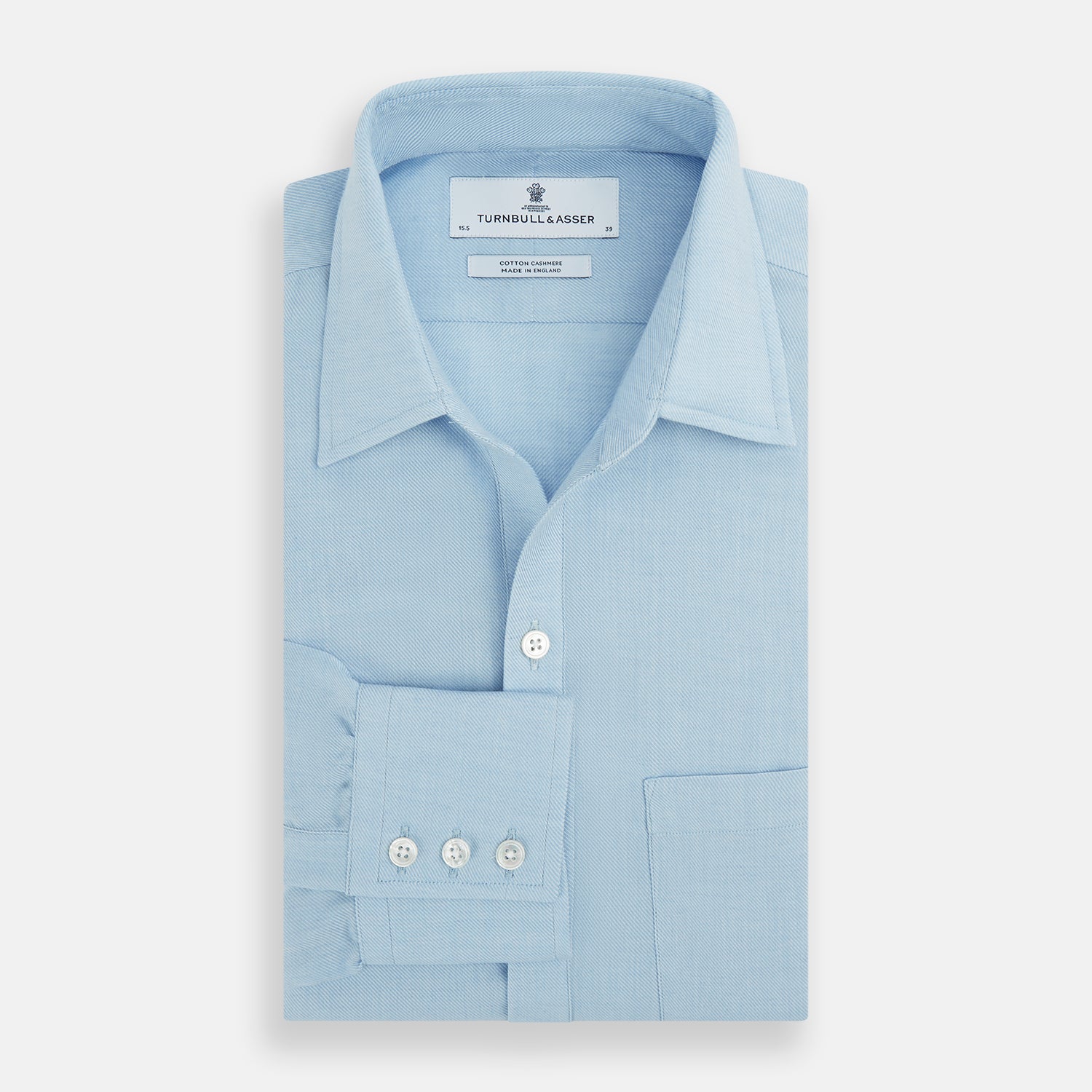 View 4 of product The Blue Cotton Cashmere Chelsea Shirt by Turnbull & Asser, a light blue long-sleeve button-up with a chest pocket, crafted from soft cotton and cashmere, is shown laid flat on a white background.
