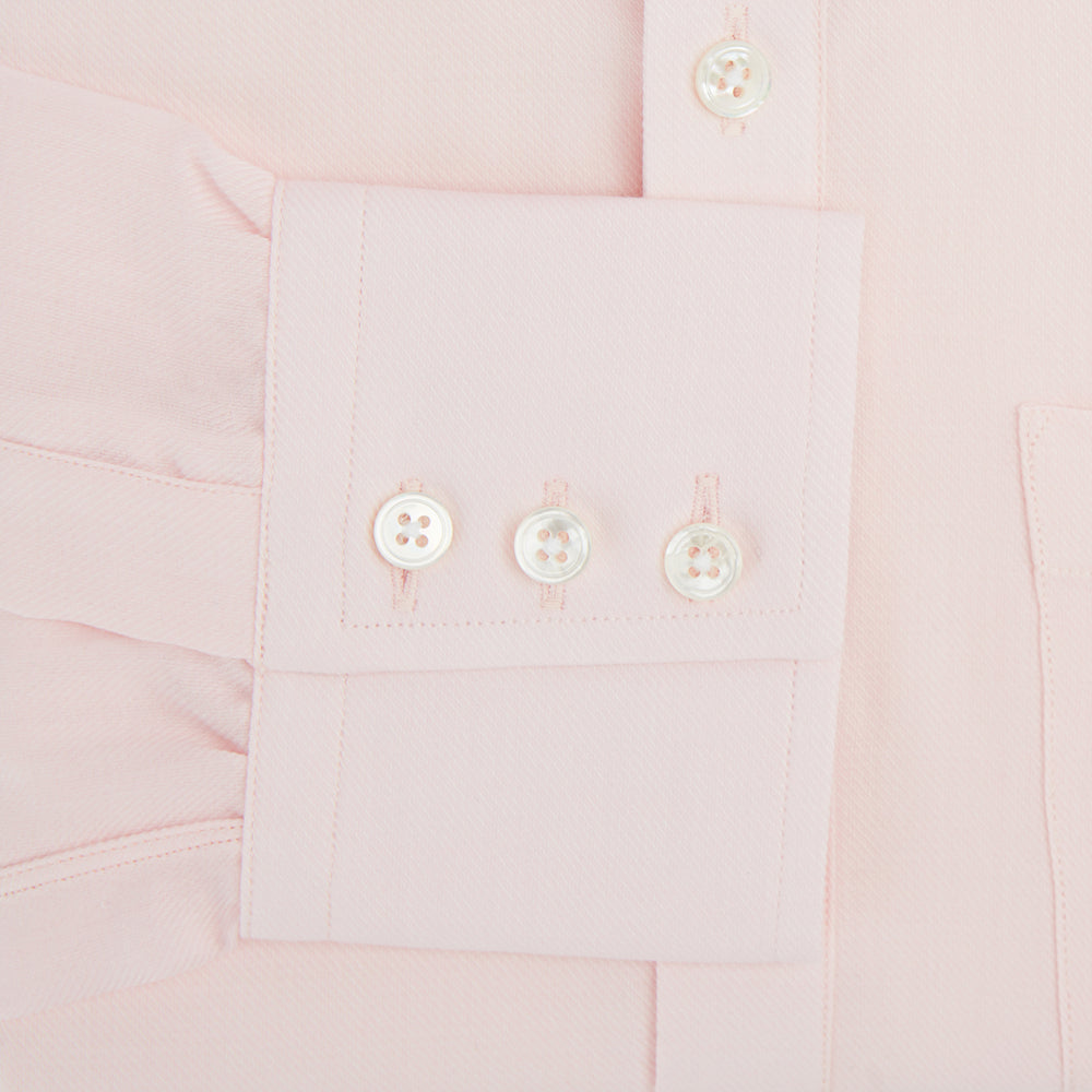 The Turnbull & Asser Pale Pink Cotton Cashmere Chelsea Shirt features long sleeves, a chest pocket, spread collar, and buttoned cuffs. Crafted from a luxurious cotton-cashmere blend, it's shown laid flat on a white background.