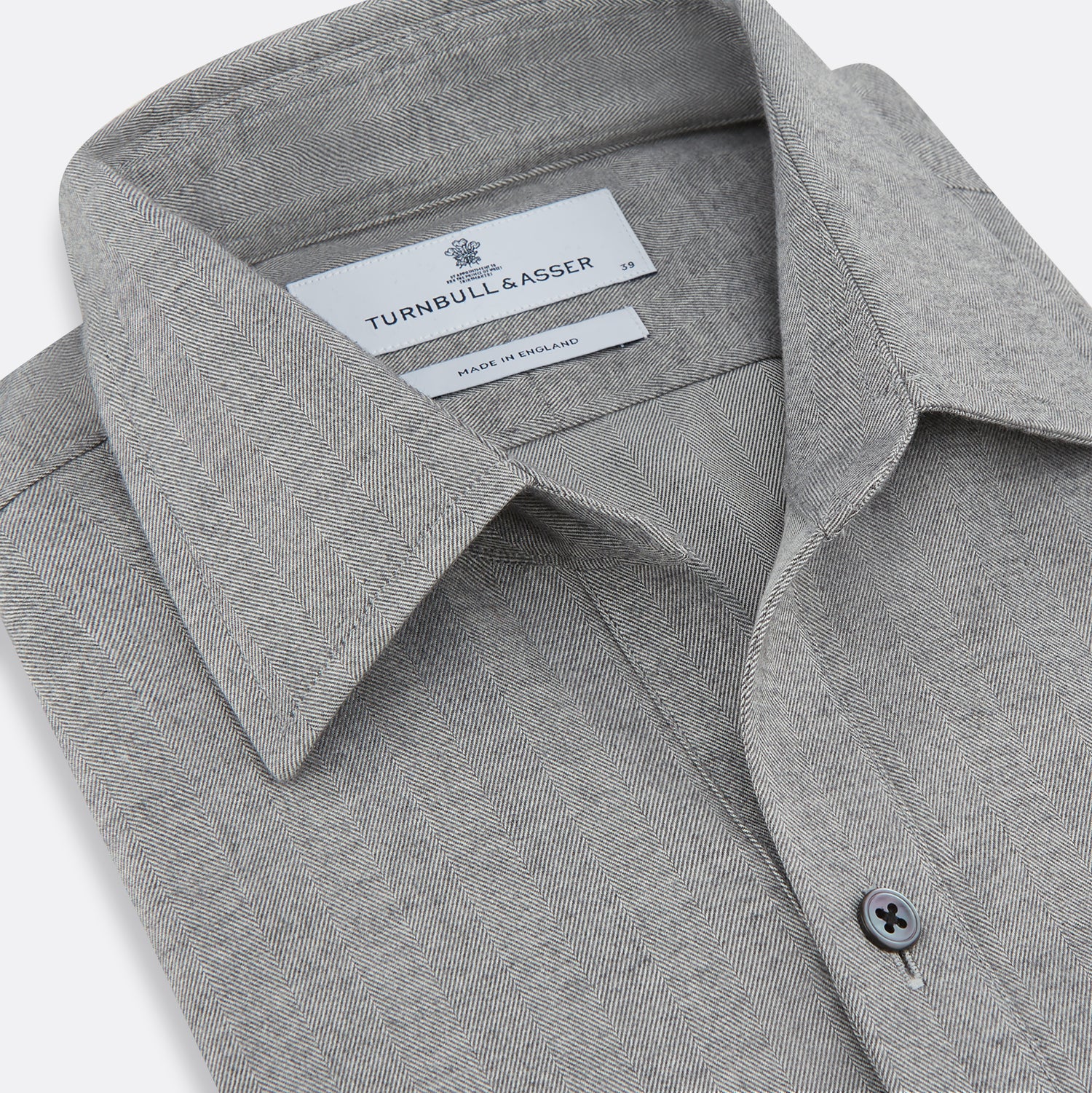 View 2 of product The Turnbull & Asser Grey Herringbone Chelsea Shirt features long sleeves, a chest pocket, classic collar, and buttoned cuffs, adding refined style to smart-casual outfits—shown here against a plain white background.