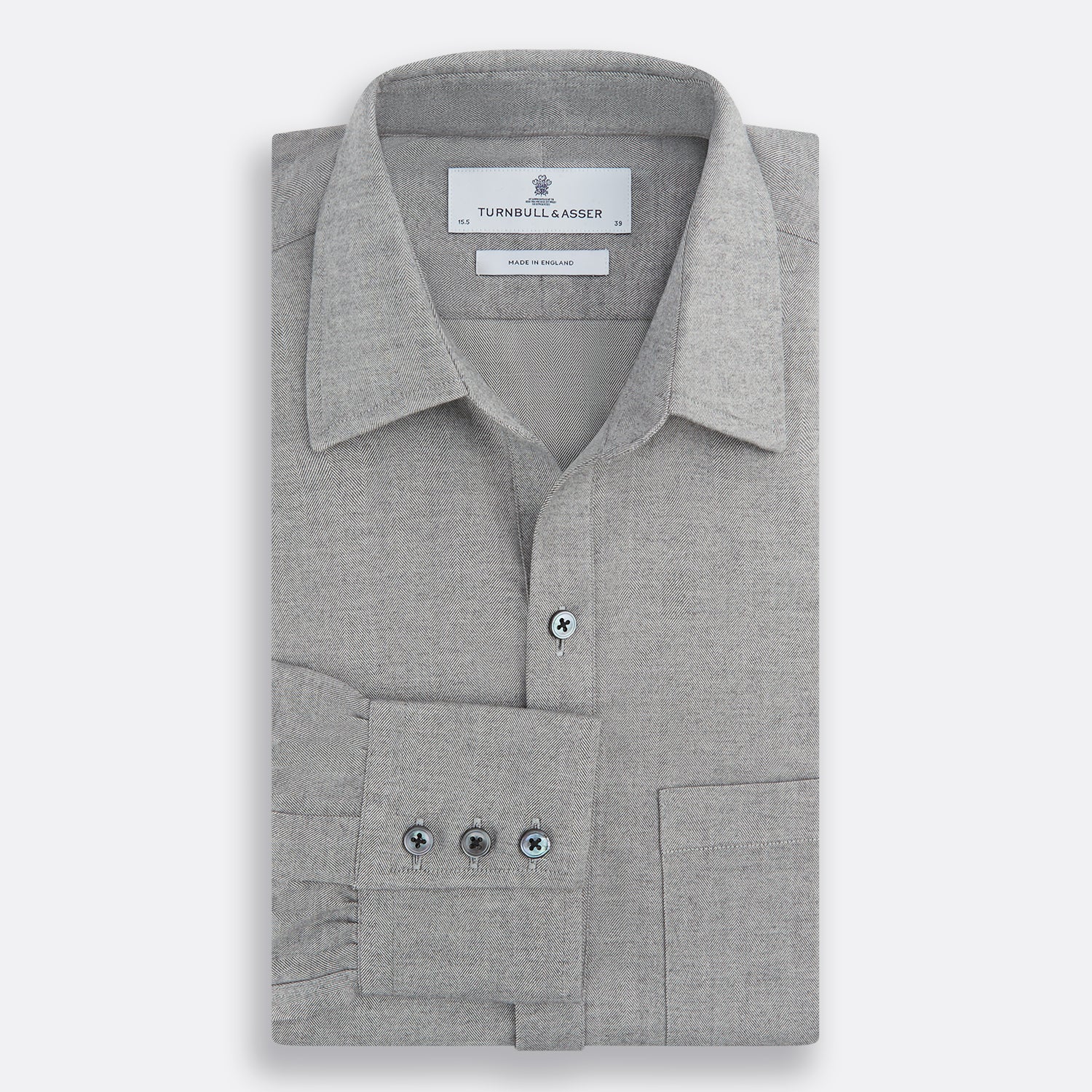 View 4 of product The Turnbull & Asser Grey Herringbone Chelsea Shirt features long sleeves, a chest pocket, classic collar, and buttoned cuffs, adding refined style to smart-casual outfits—shown here against a plain white background.