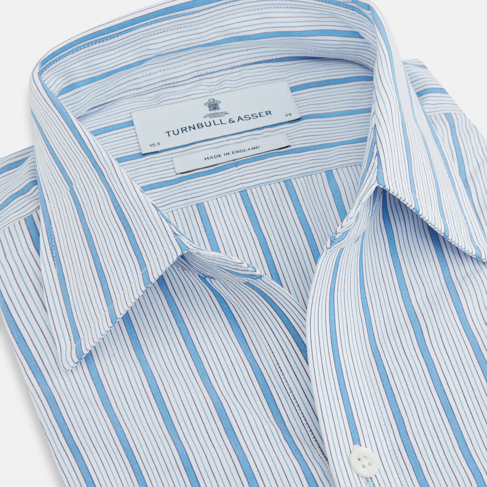 The Turnbull & Asser Blue Multi Track Stripe Chelsea Shirt features long sleeves, a light blue multi-stripe design, a chest pocket, open collar, and buttoned cuffs, shown laid flat on a white background.