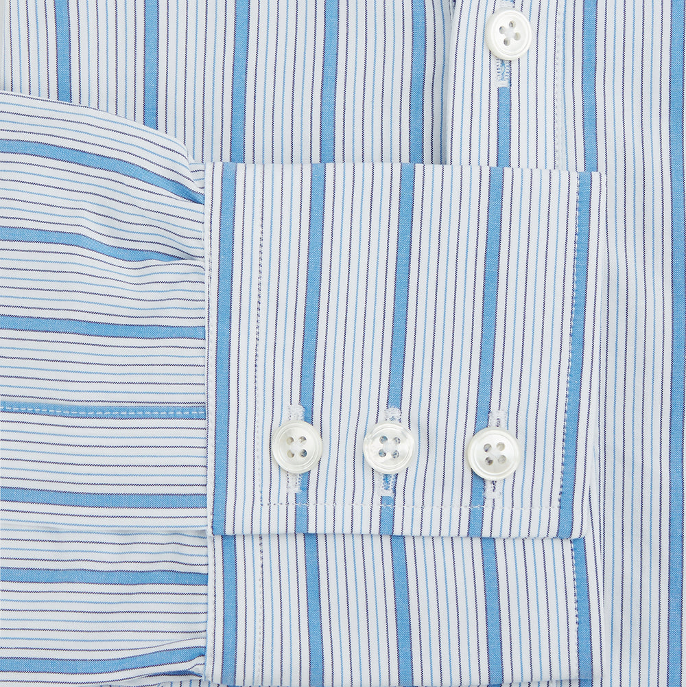 The Turnbull & Asser Blue Multi Track Stripe Chelsea Shirt features long sleeves, a light blue multi-stripe design, a chest pocket, open collar, and buttoned cuffs, shown laid flat on a white background.