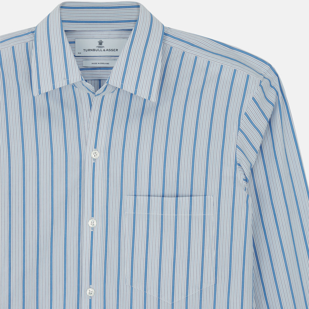 The Turnbull & Asser Blue Multi Track Stripe Chelsea Shirt features long sleeves, a light blue multi-stripe design, a chest pocket, open collar, and buttoned cuffs, shown laid flat on a white background.