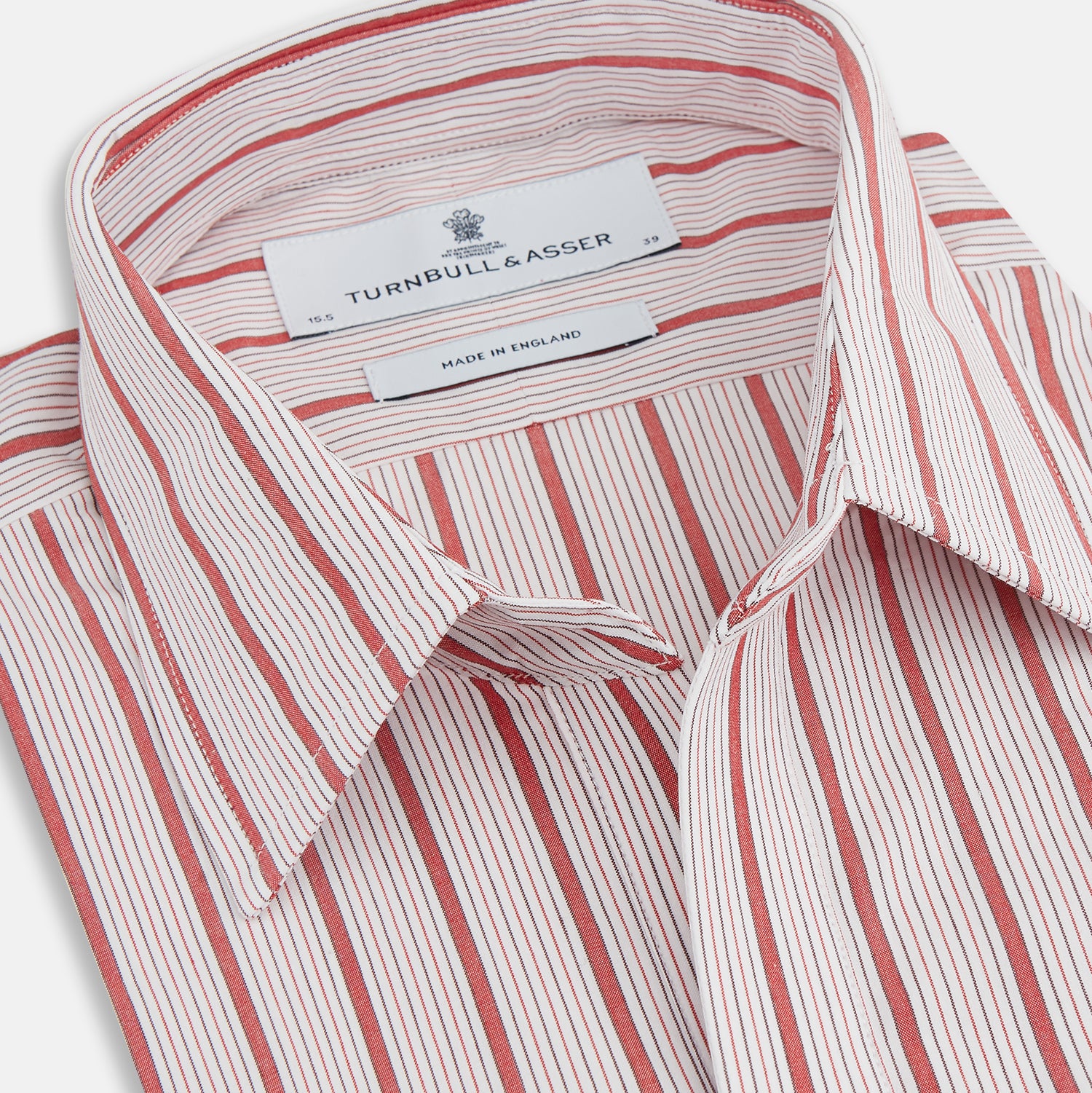 View 2 of product The Turnbull & Asser Red Multi Track Stripe Chelsea Shirt features a classic open collar, long sleeves, red vertical stripes on white, and a left chest pocket—laid flat against a plain background.