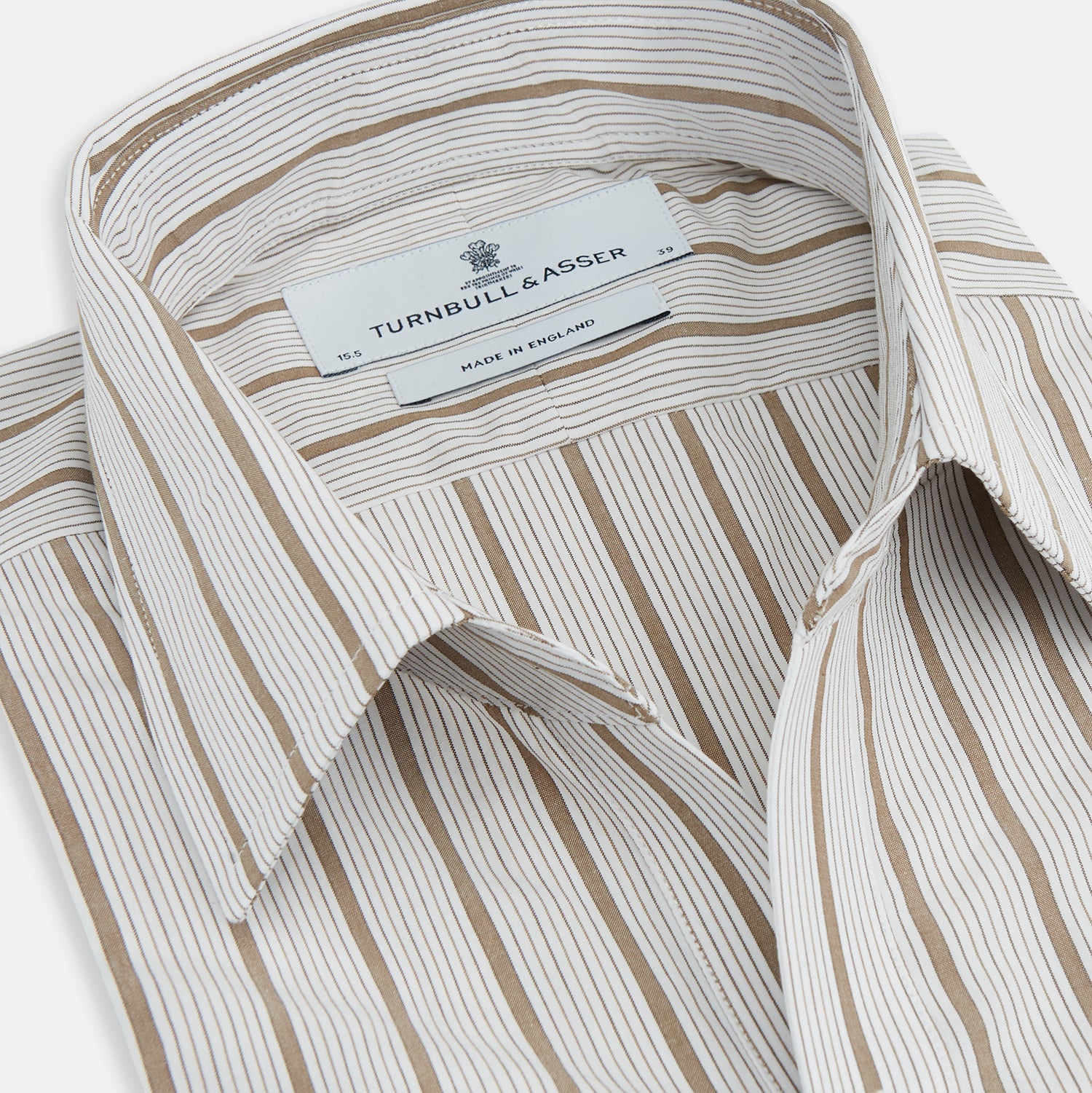 View 2 of product The Turnbull & Asser Brown Multi Track Stripe Chelsea Shirt features long sleeves, multi-track tan stripes, a left chest pocket, and an open T&A collar, shown laid flat on a white background.