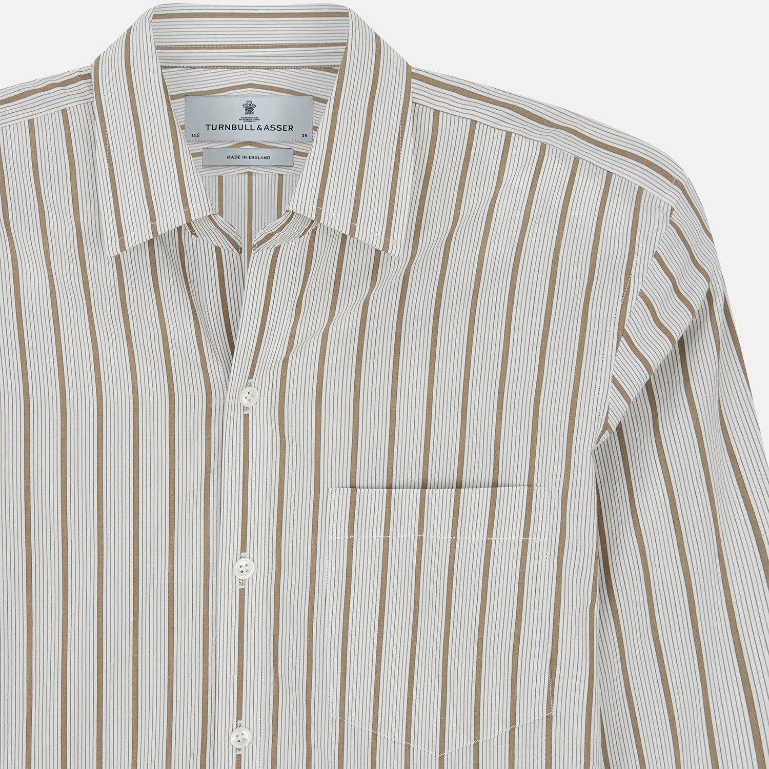 View 4 of product The Turnbull & Asser Brown Multi Track Stripe Chelsea Shirt features long sleeves, multi-track tan stripes, a left chest pocket, and an open T&A collar, shown laid flat on a white background.