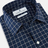 View 2 of product The Turnbull & Asser UK Windsor Navy Regular Fit Shirt in Cotton is a classic men's long-sleeve, button-up shirt featuring a navy blue base with a white grid pattern, displayed laid flat on a white background.