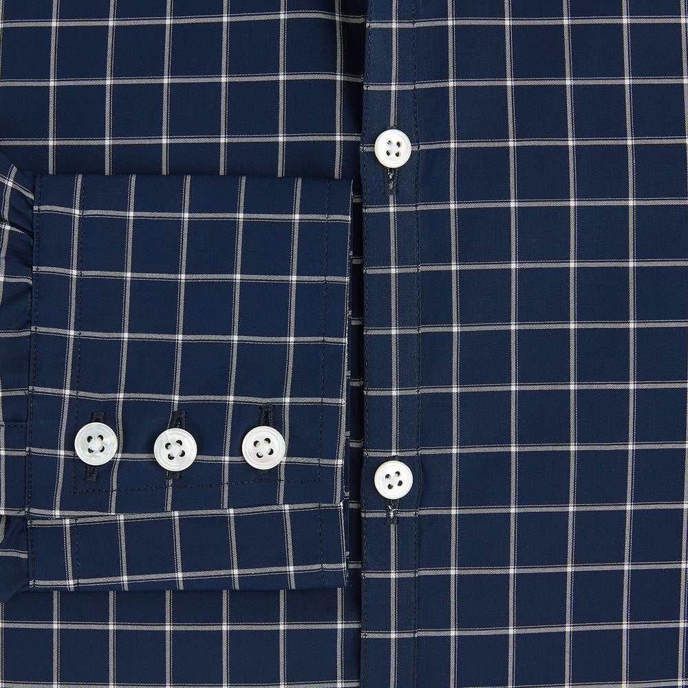 The Turnbull & Asser UK Windsor Navy Regular Fit Shirt in Cotton is a classic men's long-sleeve, button-up shirt featuring a navy blue base with a white grid pattern, displayed laid flat on a white background.