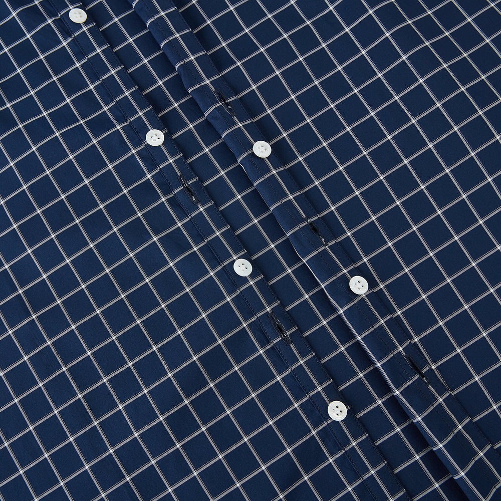 The Turnbull & Asser UK Windsor Navy Regular Fit Shirt in Cotton is a classic men's long-sleeve, button-up shirt featuring a navy blue base with a white grid pattern, displayed laid flat on a white background.