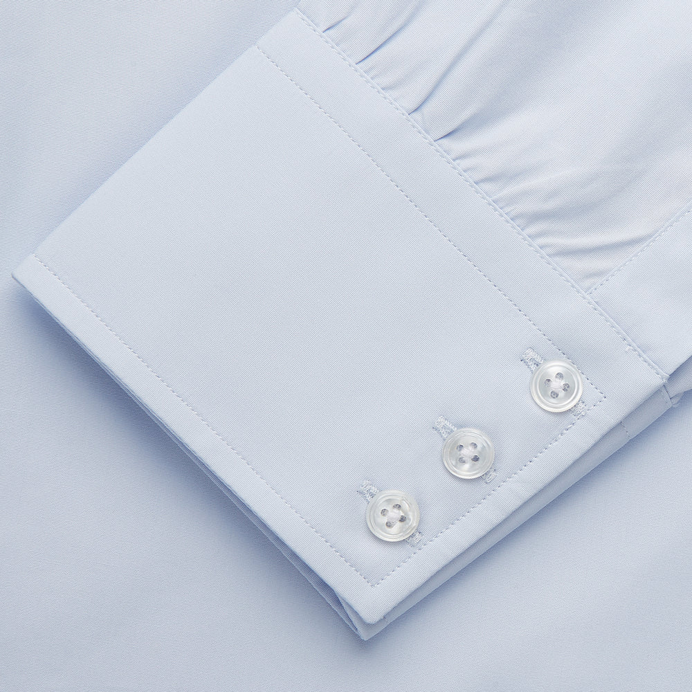 The Turnbull & Asser Tailored Fit Light Blue Cotton Shirt features a Kent collar, buttoned front, and 3-button cuffs, ideal for pairing with a navy suit and shown laid flat on a white background.