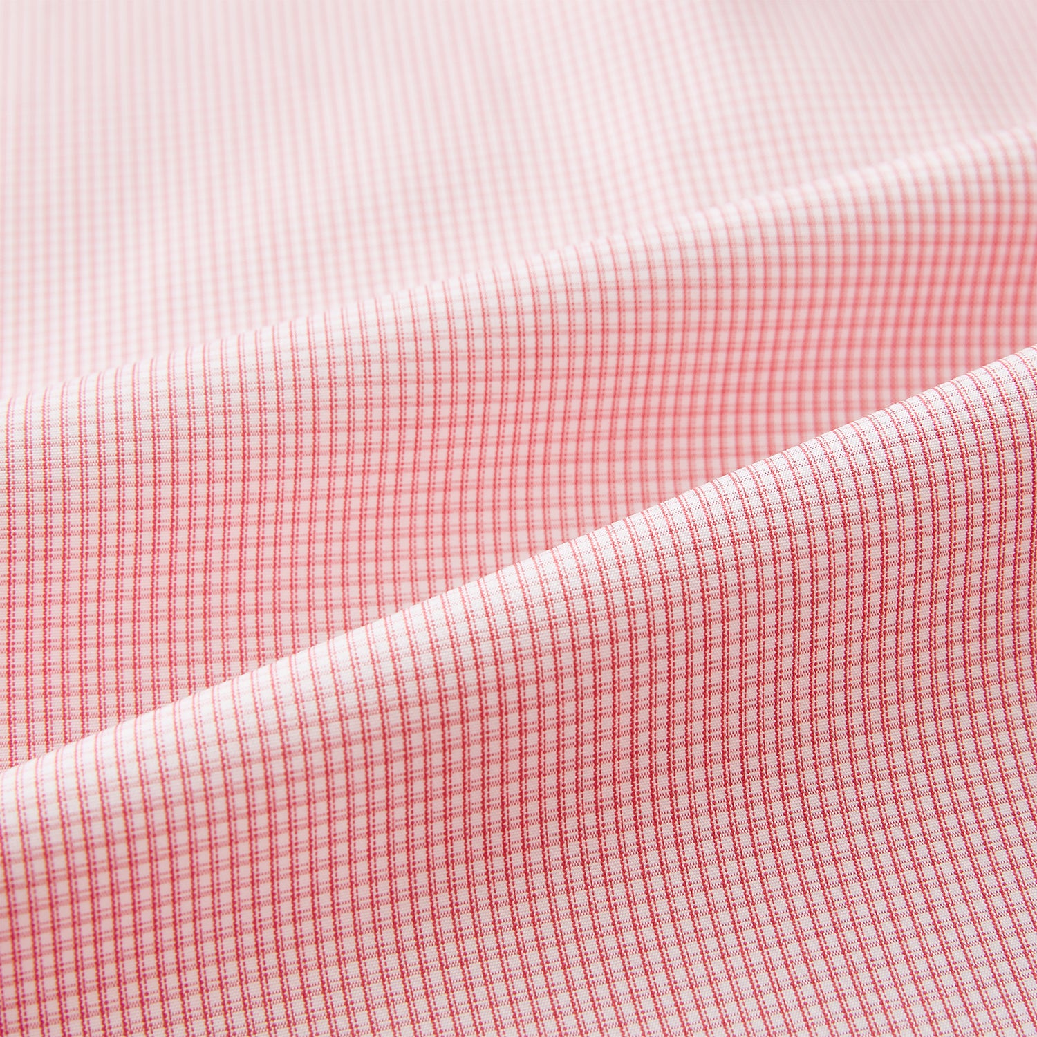 View 6 of product The Turnbull & Asser UK CORAL COTTON MINI CHECKED SHIRT is a light pink long-sleeve button-up shirt with a Kent collar, white buttons, and three-button cuffs, shown on a plain white background.