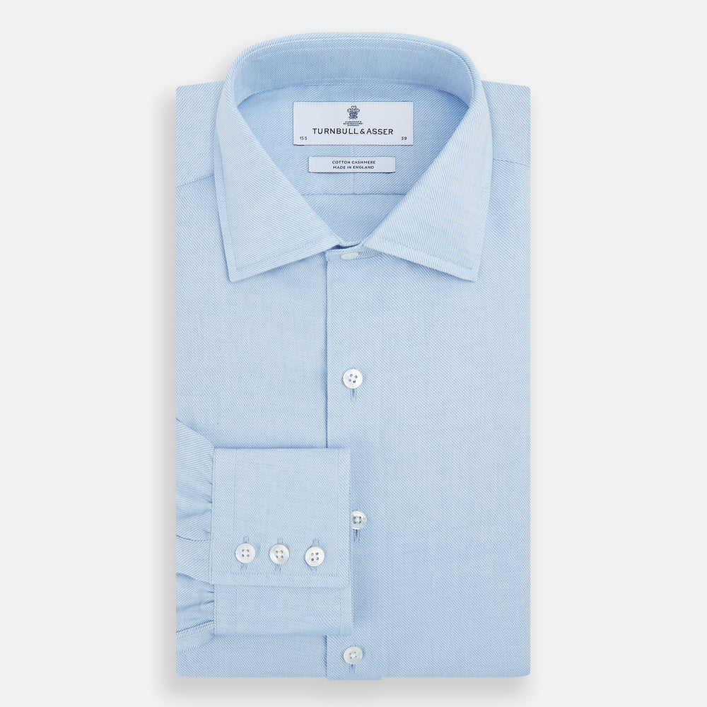 The Turnbull & Asser Tailored Fit Blue Cotton Cashmere Belgravia Shirt features a classic collar, button-down front, and buttoned cuffs, shown laid flat on a white background for a refined, formal look.