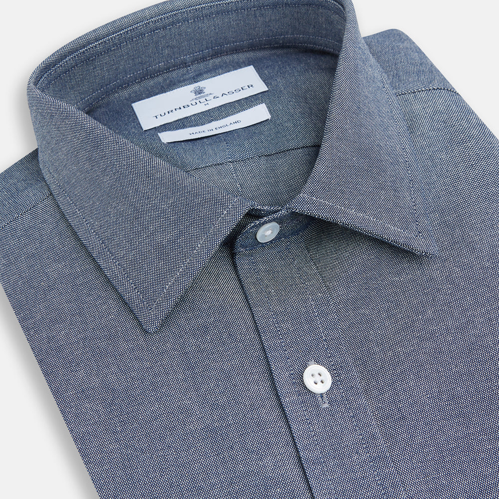 The Turnbull & Asser Steel Blue Richmond Shirt is a long-sleeved, button-up dress shirt with a Derby collar, single chest pocket, and buttoned cuffs—shown on a plain white background.