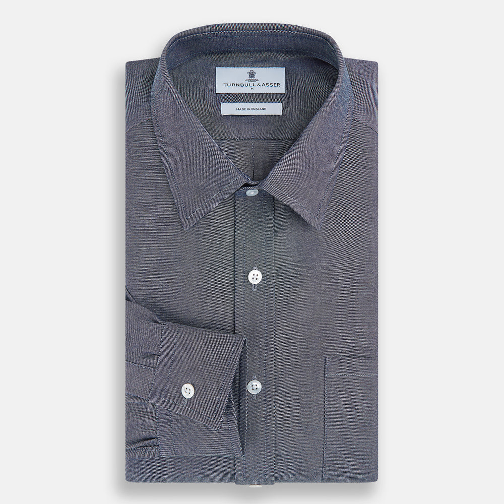 The Turnbull & Asser Steel Blue Richmond Shirt is a long-sleeved, button-up dress shirt with a Derby collar, single chest pocket, and buttoned cuffs—shown on a plain white background.