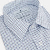 View 2 of product The Turnbull & Asser Blue Double Graph Check Richmond Shirt features a light blue and white check pattern, front pocket, Derby collar, buttoned cuffs, and long sleeves, shown laid flat on a white background.