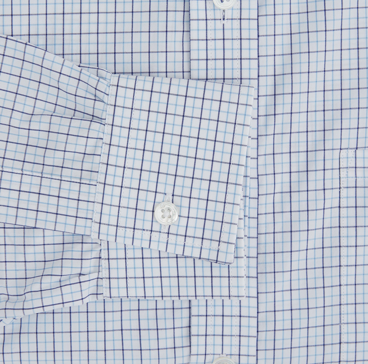 View 3 of product The Turnbull & Asser Blue Double Graph Check Richmond Shirt features a light blue and white check pattern, front pocket, Derby collar, buttoned cuffs, and long sleeves, shown laid flat on a white background.