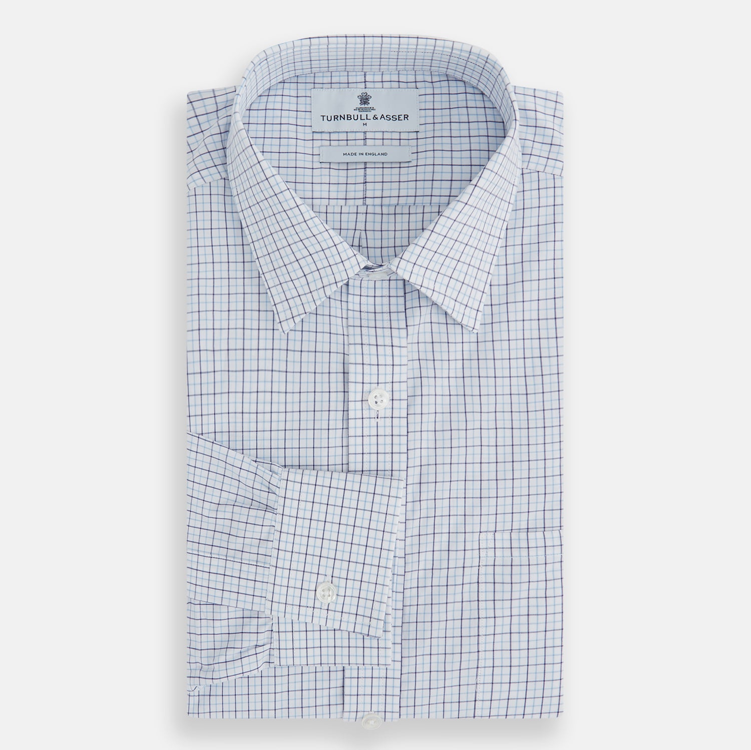 View 4 of product The Turnbull & Asser Blue Double Graph Check Richmond Shirt features a light blue and white check pattern, front pocket, Derby collar, buttoned cuffs, and long sleeves, shown laid flat on a white background.