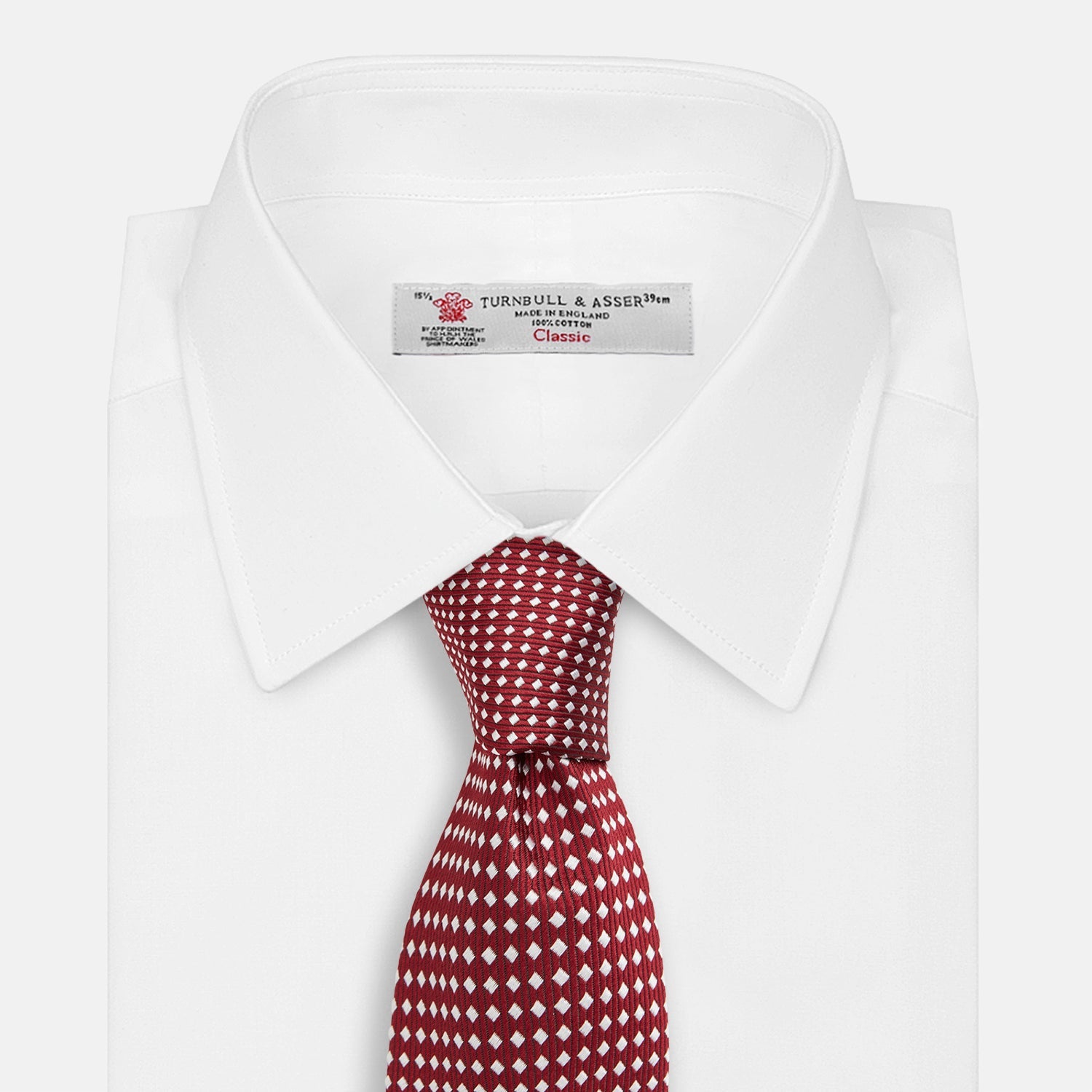 View 2 of product The Turnbull & Asser Slim Burgundy and White Diamond Silk Tie, shown rolled on a white background, features a repeating pattern of small white diamonds—an ideal accessory to complement any office shirt.