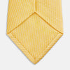 View 4 of product The Turnbull & Asser Yellow Lace Silk Tie, featuring a light yellow hue and subtle texture, is neatly rolled and displayed on a plain white background.