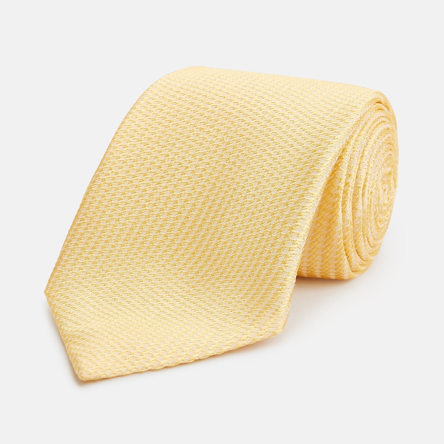 View 1 of product The Turnbull & Asser Yellow Lace Silk Tie, featuring a light yellow hue and subtle texture, is neatly rolled and displayed on a plain white background.