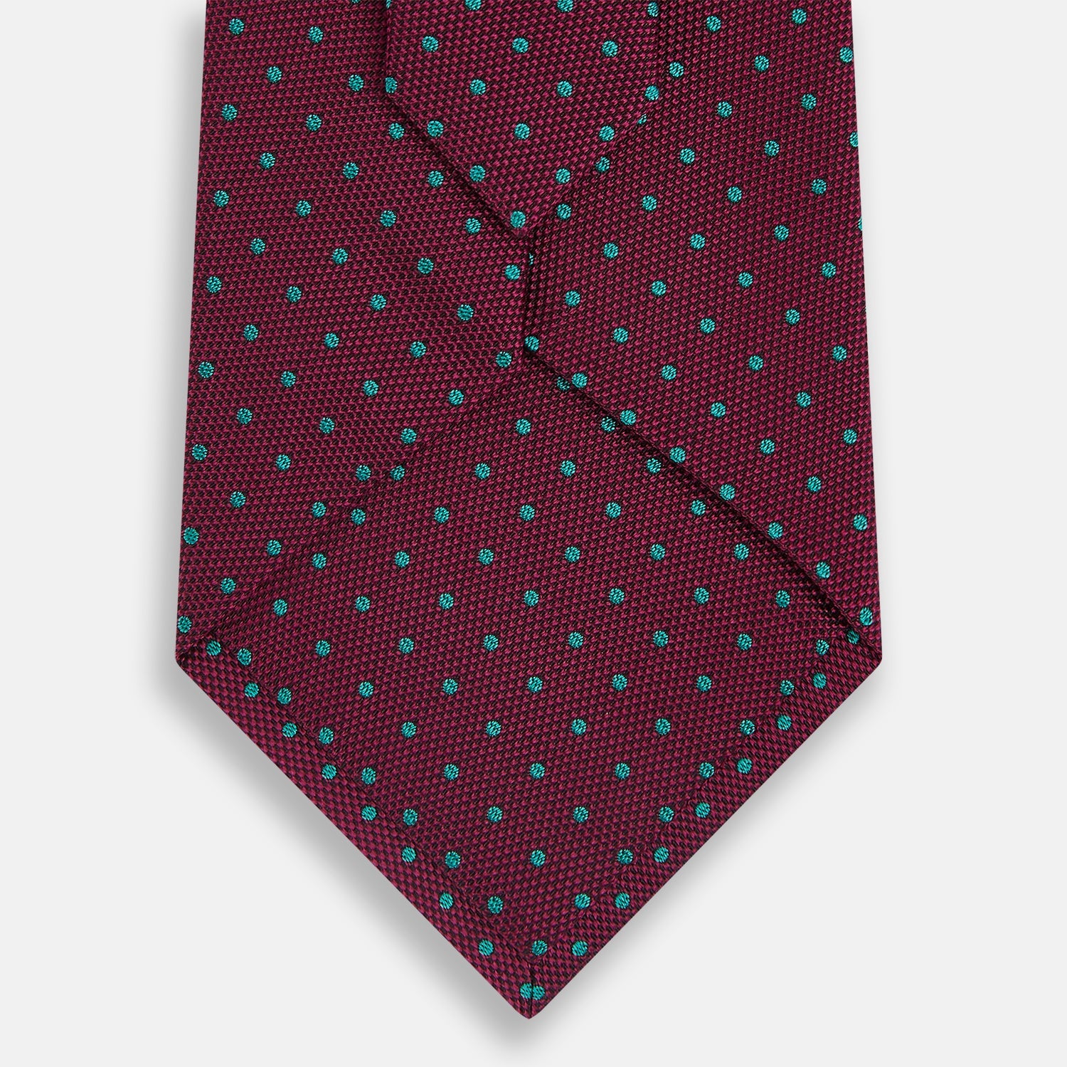 View 3 of product A rolled-up Turnbull & Asser Green and Magenta Micro Dot Silk Tie, featuring small, evenly spaced magenta dots on green silk, displayed on a plain white background—an ideal accessory for sophisticated outfits.