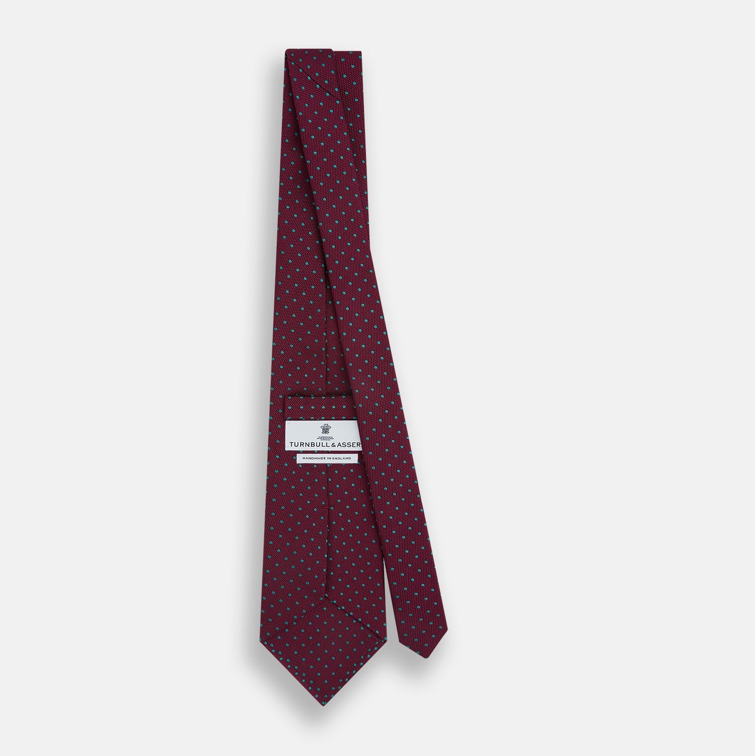 View 4 of product A rolled-up Turnbull & Asser Green and Magenta Micro Dot Silk Tie, featuring small, evenly spaced magenta dots on green silk, displayed on a plain white background—an ideal accessory for sophisticated outfits.
