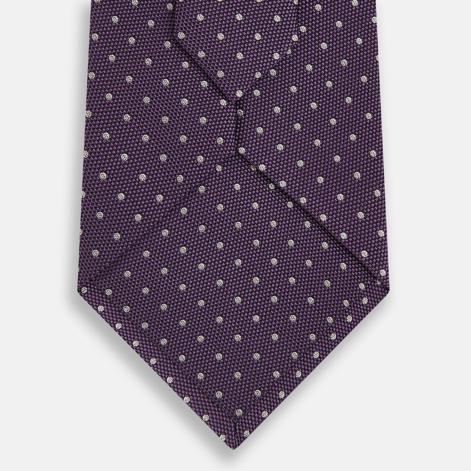 View 3 of product The Turnbull & Asser Lilac and Purple Micro Dot Silk Tie, featuring a subtle white micro-dot pattern, is rolled up and displayed on a white background—an essential addition to any polished wardrobe.