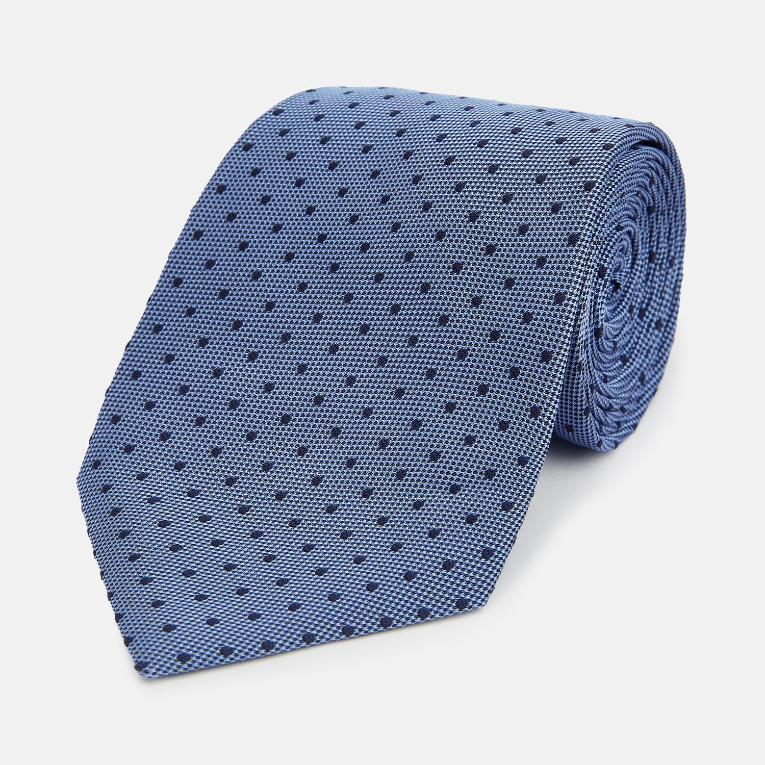 View 1 of product The Turnbull & Asser Navy and Blue Micro Dot Silk Tie is shown rolled up, featuring a steel blue color with small navy blue dots, on a plain white background.