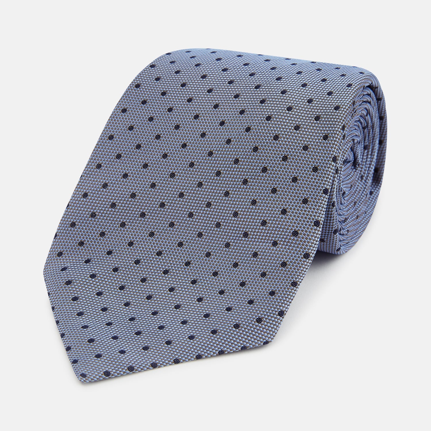 View 1 of product The Turnbull & Asser Navy and Pale Blue Micro Dot Silk Tie features a pattern of small, evenly spaced dots and is elegantly rolled on a plain white background.