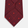 View 3 of product A rolled Tulip Red Concentric Diamond Printed Silk Tie in red silk featuring a dark blue concentric diamond pattern.