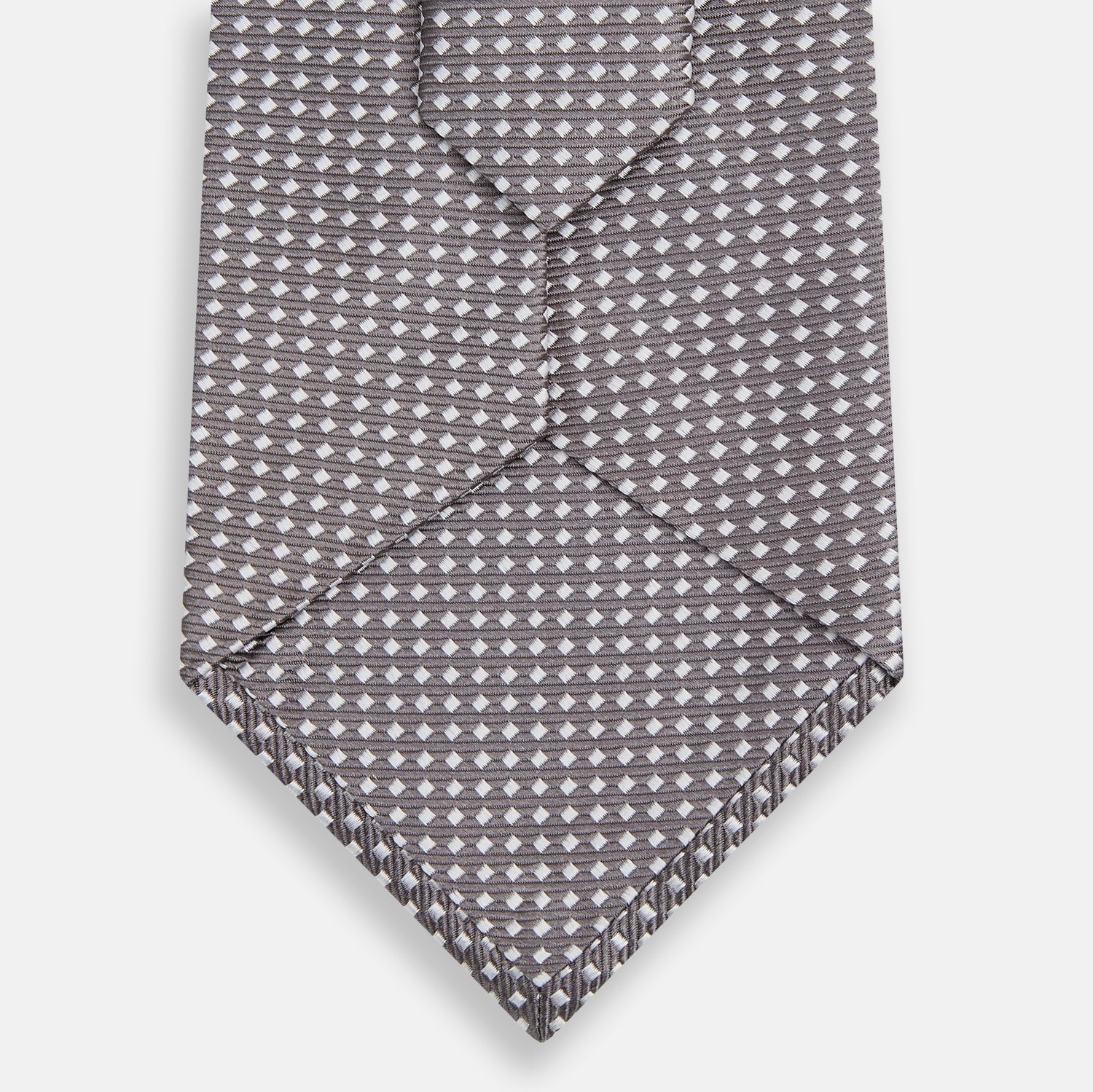 View 3 of product The Turnbull & Asser Grey and White Diamond Silk Tie features a refined geometric pattern, combining silver triangles on a white background for an elegant look.