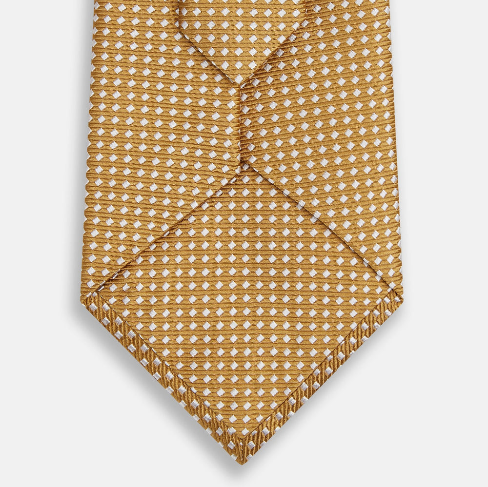 A Turnbull & Asser Light Brown and White Diamond Silk Tie, featuring a refined white geometric pattern, ideal for modern office wear, shown rolled on a plain white background.